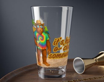 May include: A clear pint glass with a cartoon orangutan wearing sunglasses, a cowboy hat, and a tie-dye shirt. The glass has the text "it's high o'clock somewhere" and a sand-like design at the bottom.