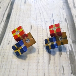 May include: A pair of gold-tone earrings with blue and red gift box charms. Each charm has a gold ribbon and a clear rhinestone.