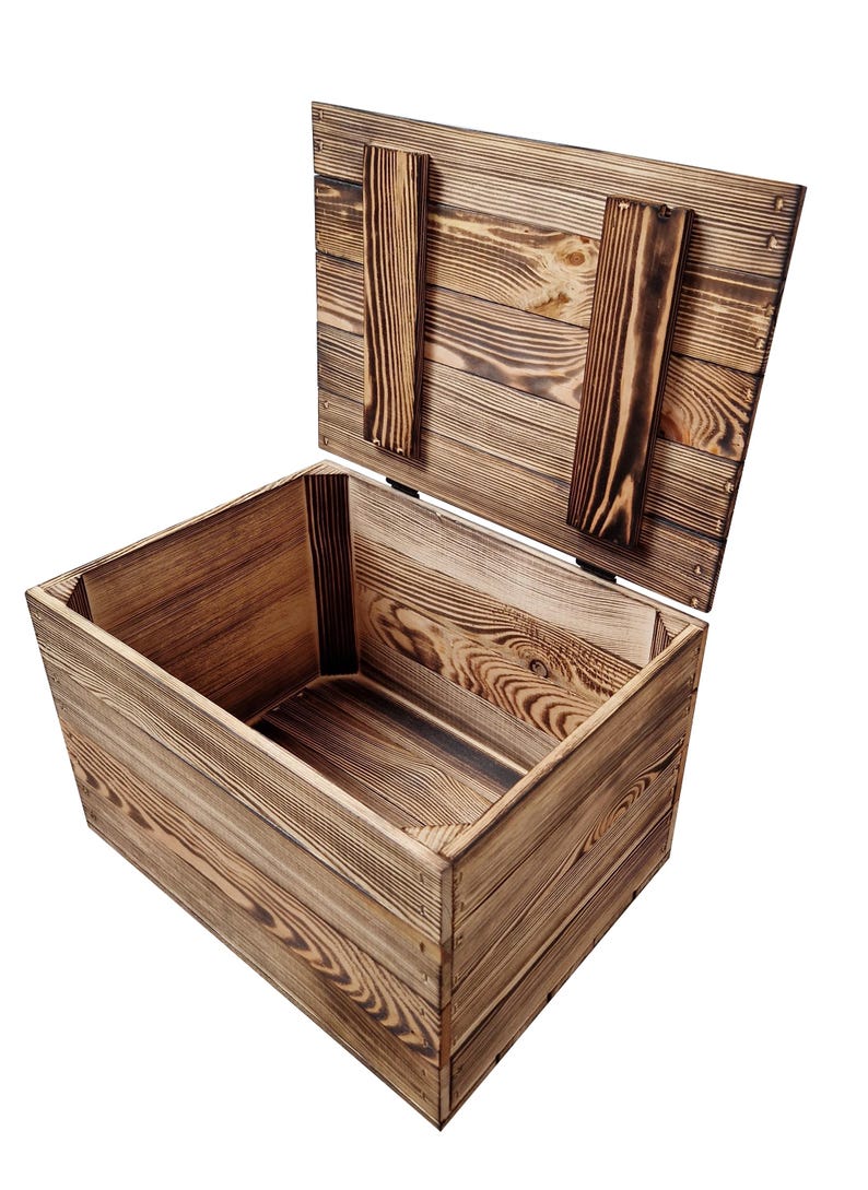 May include: A rustic wooden storage box with a hinged lid, open to reveal the interior. The box is constructed from light brown wood with visible grain and darker, charred accents. The lid is propped open with two wooden supports.