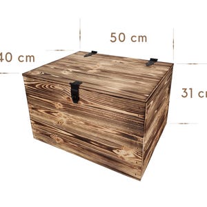 K&ouml;nnte beinhalten: Eine Holzkiste mit dunkelbraunem Finish. Die Kiste ist rechteckig und misst 50 cm in der L&auml;nge, 40 cm in der Breite und 31 cm in der H&ouml;he. Sie verf&uuml;gt &uuml;ber einen Metallverschluss und Scharniere.