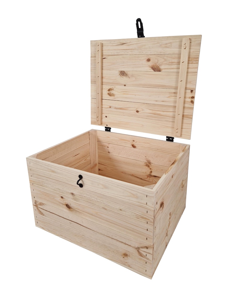 K&ouml;nnte beinhalten: Eine helle Holzkiste mit offenem Deckel. Die Kiste besteht aus Holzbrettern mit sichtbaren Knoten und Maserungen. Sie hat einen schwarzen Riegel und einen Griff. Der Deckel ist leicht ge&ouml;ffnet und gibt den Blick auf das leere Innere frei.