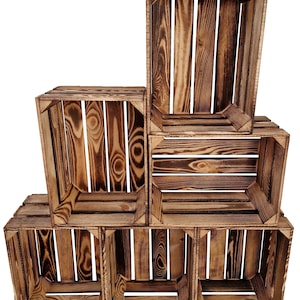 Peut inclure: Six caisses en bois empilées, avec une finition rustique de bois brûlé. Les caisses rectangulaires ont des côtés et des coins à lattes, mettant en valeur le grain naturel du bois. Idéales pour le stockage ou l'exposition.