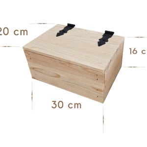 May include: A light-colored wooden box with a hinged lid and black metal hardware. The box measures 11.8 inches long, 7.9 inches wide, and 6.3 inches high. The box is made of light-colored wood.