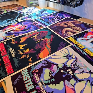 May include: A collection of colorful posters featuring monster illustrations. The posters have a variety of designs, including images of creatures and text that reads "Monster Hunting!" and "Splish Splash!"