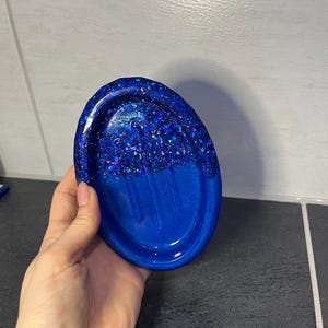 Könnte beinhalten: Eine blaue, ovale Seifenschale mit glitzerndem Oberteil und glattem Boden.