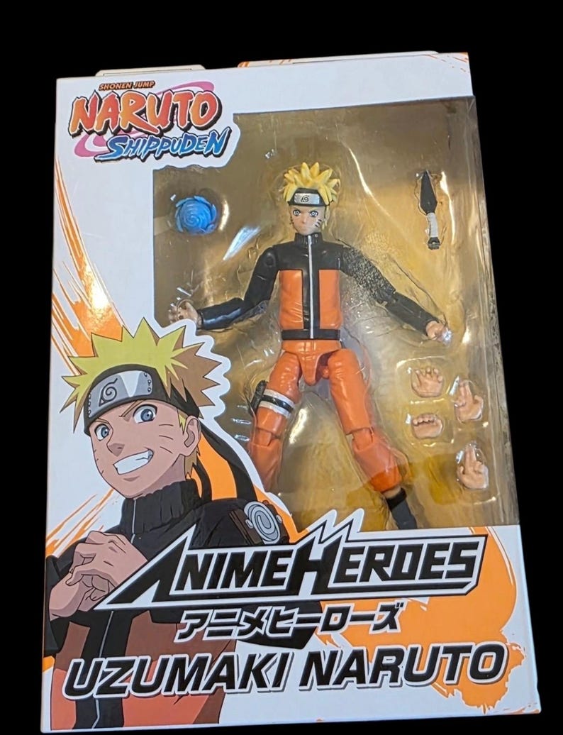 Op de afbeelding: Een Anime Heroes actiefiguur van Uzumaki Naruto uit Naruto Shippuden in de doos. De figuur is oranje en zwart, met verwisselbare handen en accessoires. De verpakking toont karakterkunst en het serielogo.