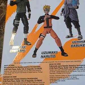 Op de afbeelding: Achterkant van een Naruto Shippuden actiefiguurverpakking met Kakashi, Naruto en Sasuke. De figuren staan in dynamische poses, met heldere kleuren en gedetailleerde ontwerpen. De verpakking bevat tekst en logo's.