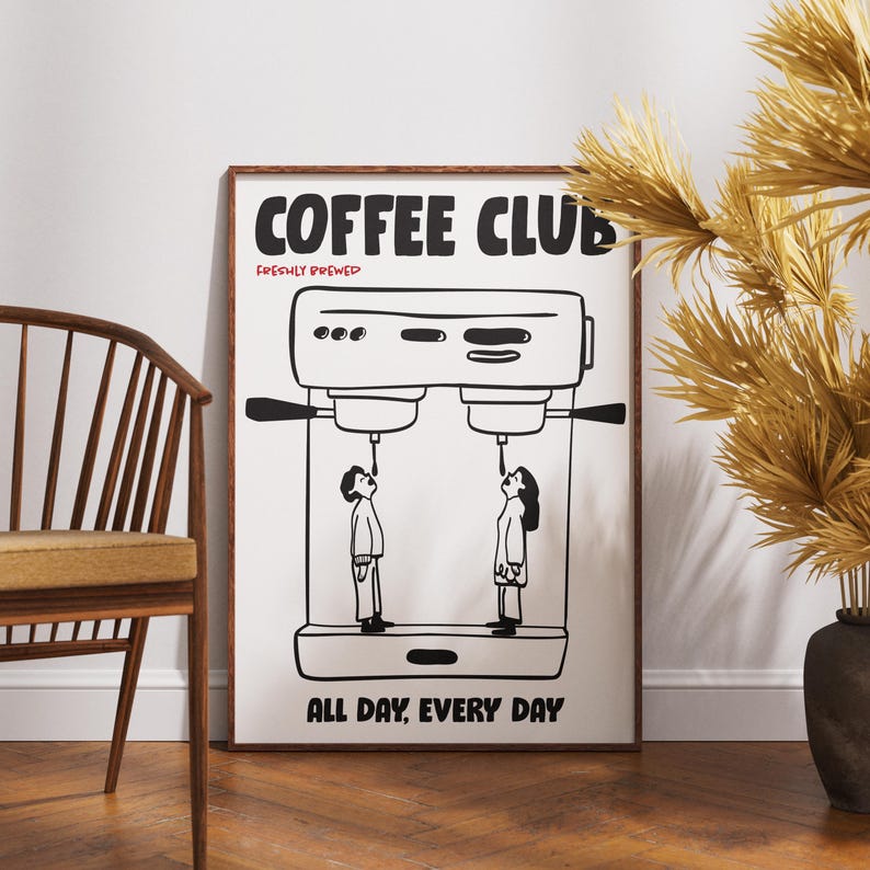 Op de afbeelding: Een ingelijste poster met een koffiethema. De poster toont een zwart-wit illustratie van een koffiemachine met twee mensen die naar de tuiten kijken. De woorden "COFFEE CLUB" en "ALL DAY, EVERY DAY" staan op de poster.