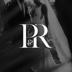 May include: Black and white image featuring a bride and groom. The bride wears a white wedding dress with a plunging neckline and a long veil. The groom is in a black suit. The letters "PR &" are in the foreground.