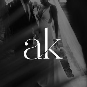 Puede incluir: Imagen en blanco y negro de una pareja el día de su boda. La novia lleva un vestido de novia blanco con escote y velo. El novio lleva un traje negro. Las letras "ak" están en primer plano.