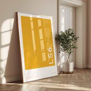 May include: A framed art print featuring a large yellow rectangle with the text "LS6" in white. The print has a gold frame and is leaning against a wall. The text "HEADINGLEY, LEEDS" and a date are printed at the bottom.