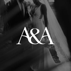 May include: Black and white photograph of a wedding. A bride in a white dress and veil stands next to a person in a suit. The letters "A&A" are in the foreground.
