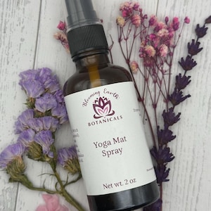 May include: A brown glass bottle with a black spray nozzle and a white label that reads "Blooming Earth Botanicals Yoga Mat Spray Net wt. 2 oz."