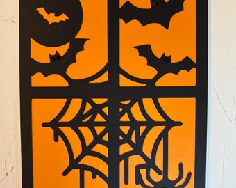 May include: Halloween-themed card with a black border, featuring an orange background with a black design. The design includes bats, a full moon, a spider web, and a spider with a red gem.