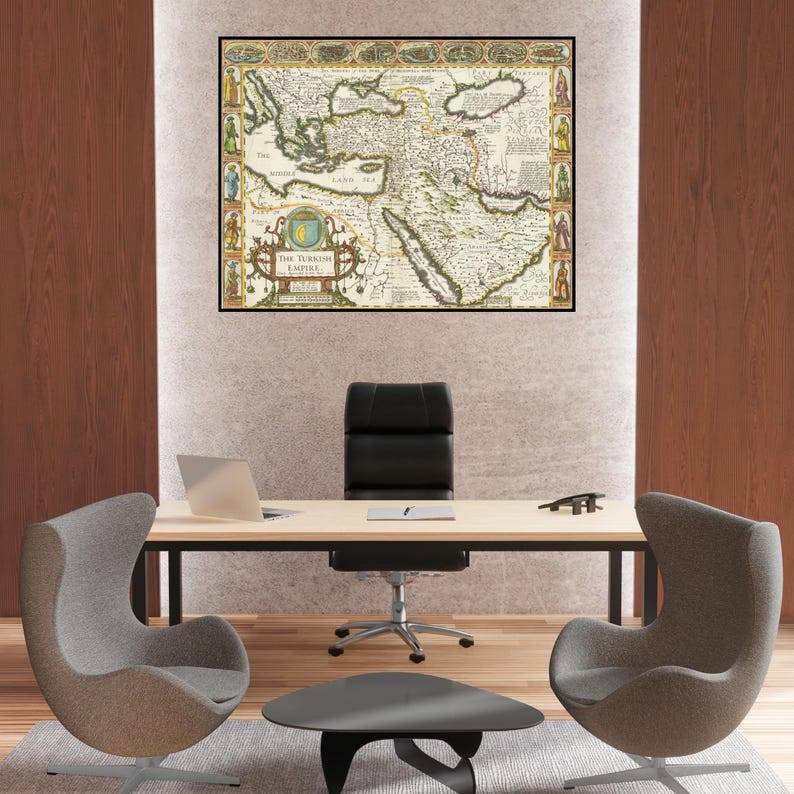 May include: A framed antique map of The Turkish Empire, featuring detailed cartography in shades of beige, green, and brown. The map is displayed above a modern office desk with a laptop, chair, and two gray egg-shaped chairs.