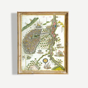 May include: A framed antique map with a detailed illustration of a city, featuring buildings, trees, and boats. The map is in shades of brown, green, and yellow, with a decorative compass rose and text. The frame is a light brown color.