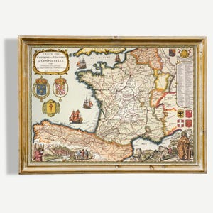 May include: Framed vintage map of France, featuring detailed cartography with intricate lines and text. The map includes illustrations of ships and coats of arms, set within a gold-colored wooden frame. The map is a historical piece.