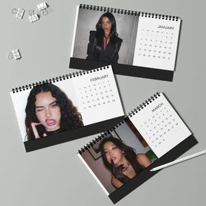 May include: A collection of three spiral-bound desk calendars, each featuring a different month and a photograph of a person. The calendars are black with white pages, and the months visible are January, February, and March.