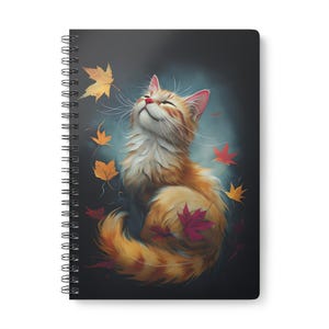 Peut inclure: Cahier à spirales avec une illustration d'un chat roux souriant, les yeux fermés, entouré de feuilles d'automne rouges, oranges et jaunes. Le chat est au centre, sur un fond sombre et flou. Un design charmant.