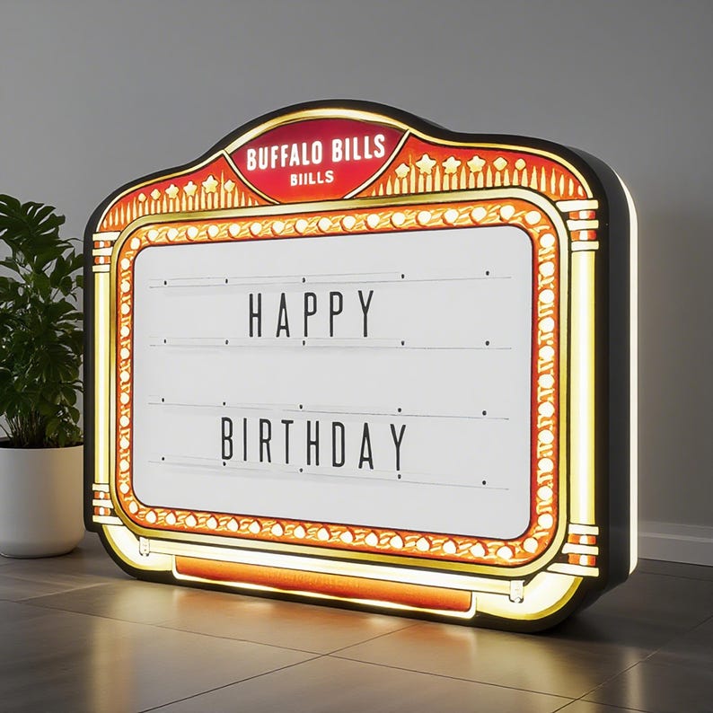 May include: A marquee-style light box with the words "HAPPY BIRTHDAY" displayed. The sign has a black frame with gold and red accents, and the top reads "BUFFALO BILLS". The light box is illuminated.