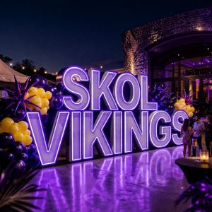 May include: Large illuminated sign that reads "SKOL VIKINGS" in purple and white. The sign is surrounded by purple and yellow balloons and decorative starbursts. The scene is set outdoors at night, with a building in the background.