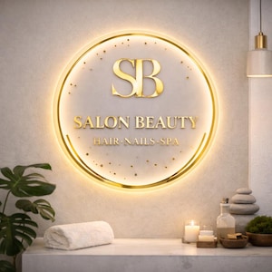 Może przedstawiać: Podświetlany, okrągły szyld ze złotą obw&oacute;dką i napisem "SB SALON BEAUTY HAIR NAILS SPA". Znak zawiera złote logo "SB" i jest umieszczony na jasnym tle. Scena obejmuje biały ręcznik, świece i akcesoria spa.