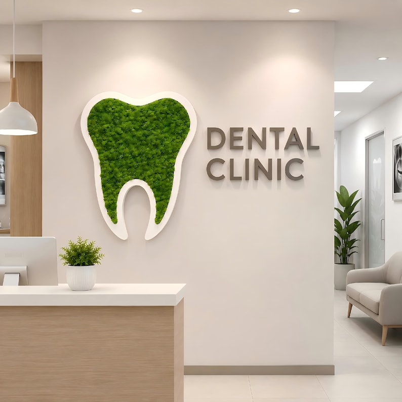 May include: A wall-mounted sign featuring a large, white-bordered tooth shape filled with vibrant green moss, positioned next to the dark gray, three-dimensional lettering that reads DENTAL CLINIC, displayed on a smooth, light-colored wall.