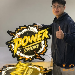May include: Illuminated sign with the words "POWER SMOKE" in yellow, outlined in black, with a lightning bolt design. The sign is black with a white and orange glow.