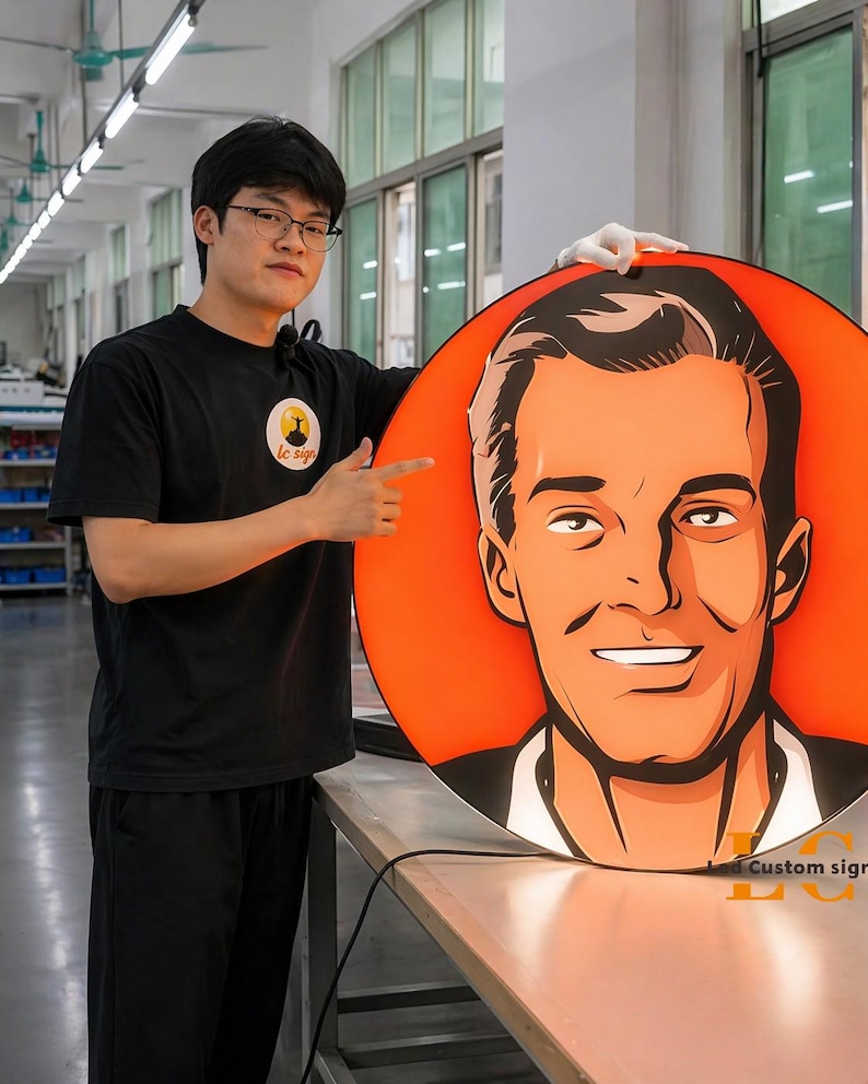 May include: A large, round custom sign featuring a stylized portrait of a man with an orange background. The sign has the text "LC Custom signs" in the bottom right corner. A person is holding the sign.