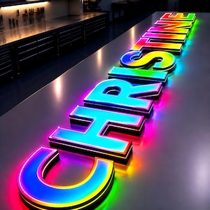 Puede incluir: Un letrero de ne&oacute;n que deletrea "CHRSTINE" en colores vibrantes. Las letras est&aacute;n delineadas con luces brillantes y multicolores, creando un efecto brillante contra una superficie reflectante. El letrero es probablemente para un negocio o evento.