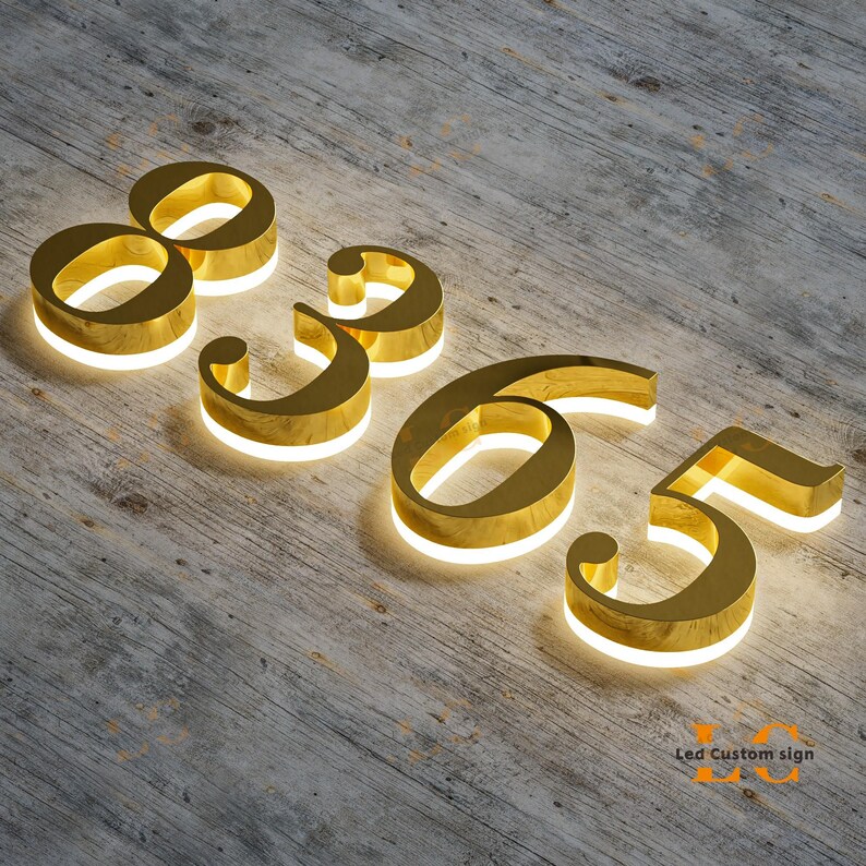 Puede incluir: N&uacute;meros dorados e iluminados 8, 9, 6 y 5 dispuestos sobre una superficie de madera. Los n&uacute;meros tienen una luz blanca brillante que perfila sus bordes interiores. El texto "LED Custom sign" es visible en la esquina inferior derecha.