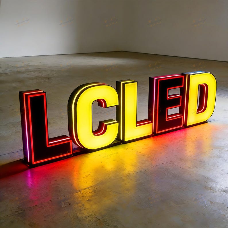 May include: Large, illuminated sign spelling out the word "LCLED". The letters are outlined in red with a black border, and the interiors glow yellow. The sign is placed on a concrete floor, casting colorful reflections.
