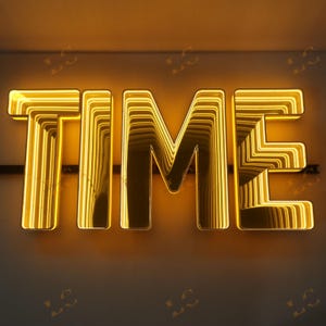 May include: A glowing, gold-colored sign spelling out the word "TIME". The letters are illuminated with a warm, yellow light, creating a layered, three-dimensional effect. The sign is mounted on a dark surface.