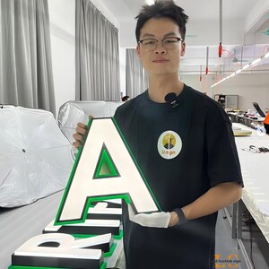 May include: A large, three-dimensional letter A sign featuring a white illuminated face, a black border, and a vibrant green trim. The letter is constructed with a thick profile and is designed for high-visibility signage applications.