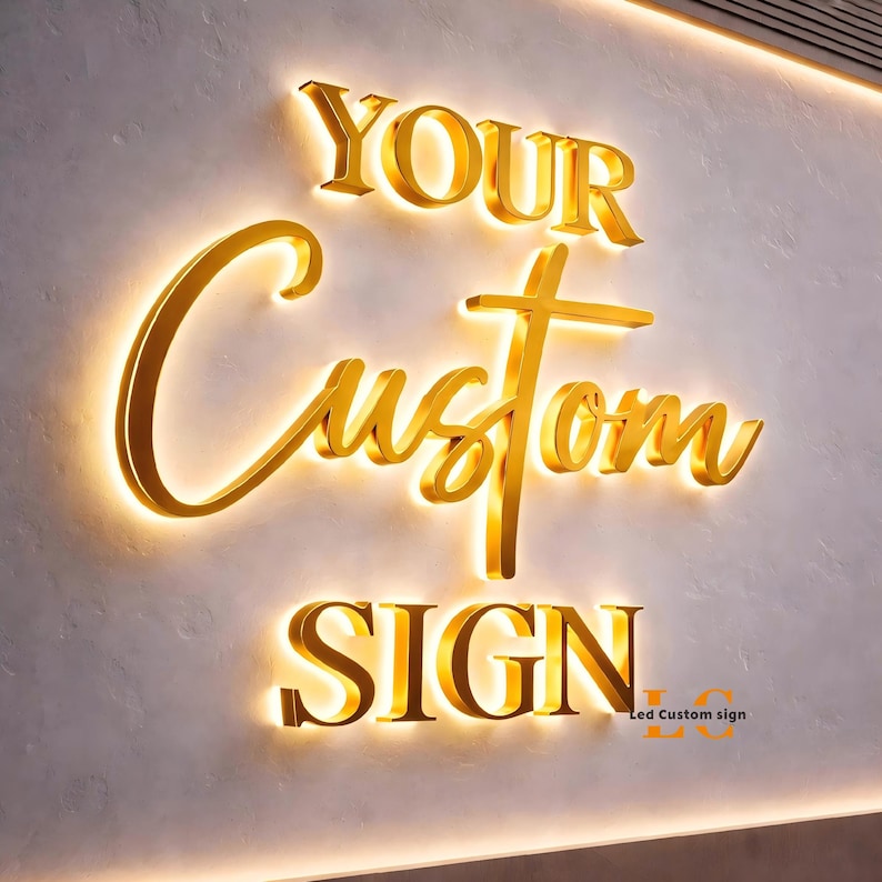 May include: A three-dimensional wall sign featuring gold-colored lettering with integrated backlighting. The text reads YOUR in a serif font, Custom in a cursive script, and SIGN in a serif font. The letters cast a warm glow onto the wall surface.