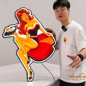 May include: A retro-style LED sign featuring a pin-up girl holding a tray with food and a coffee cup. The sign has a black outline with a red dress and a black and white top. The sign is illuminated with a bright white light.