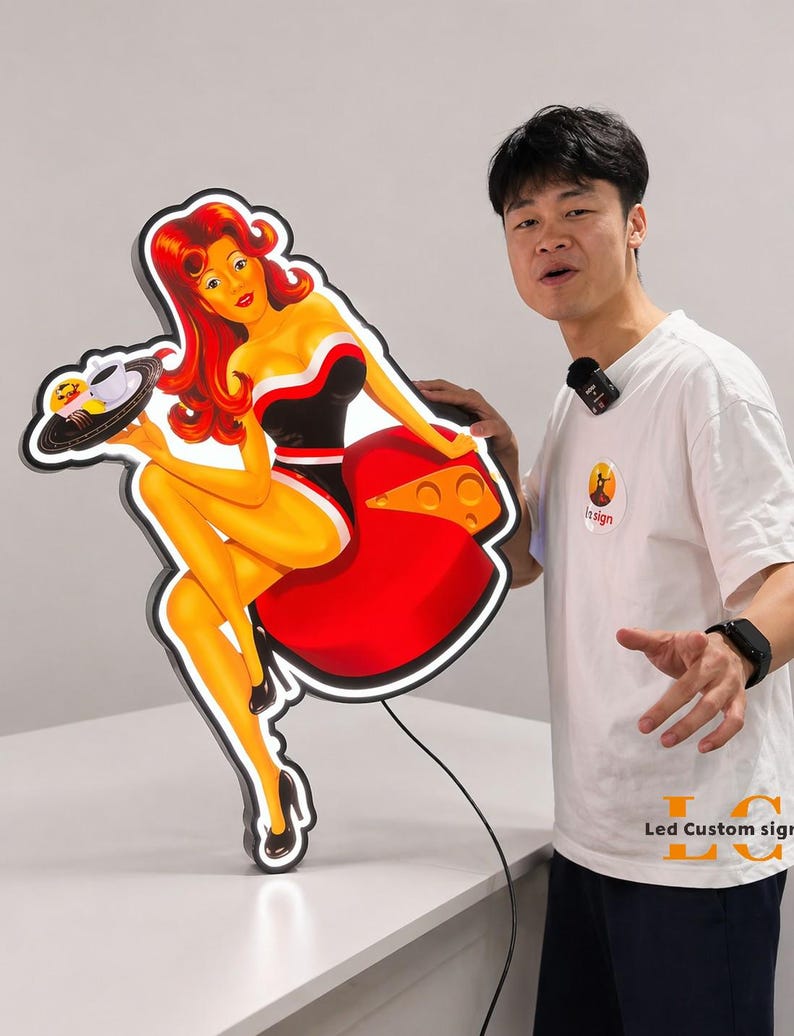 May include: A retro-style LED sign featuring a pin-up girl holding a tray with food and a coffee cup. The sign has a black outline with a red dress and a black and white top. The sign is illuminated with a bright white light.