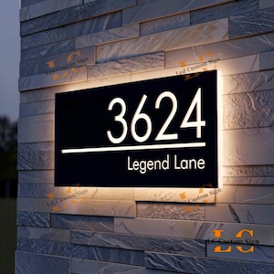 May include: A black illuminated address sign with the numbers "3624" and the text "Legend Lane" in white. The sign is mounted on a stone wall and has a bright, glowing border.