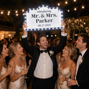 May include: A rectangular, white, illuminated marquee sign with a black border and small LED lights around the edge. The sign features the text "Introducing Mr. & Mrs. Parker" in black lettering, with the date "08.17.2024" printed below in black.