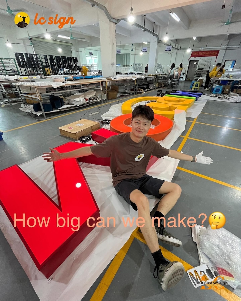 May include: A large, multi-colored, three-dimensional channel letter sign spelling out a word, featuring a bright red letter V in the foreground. The sign includes yellow, orange, and blue letters. Text on the image reads: How big can we make?