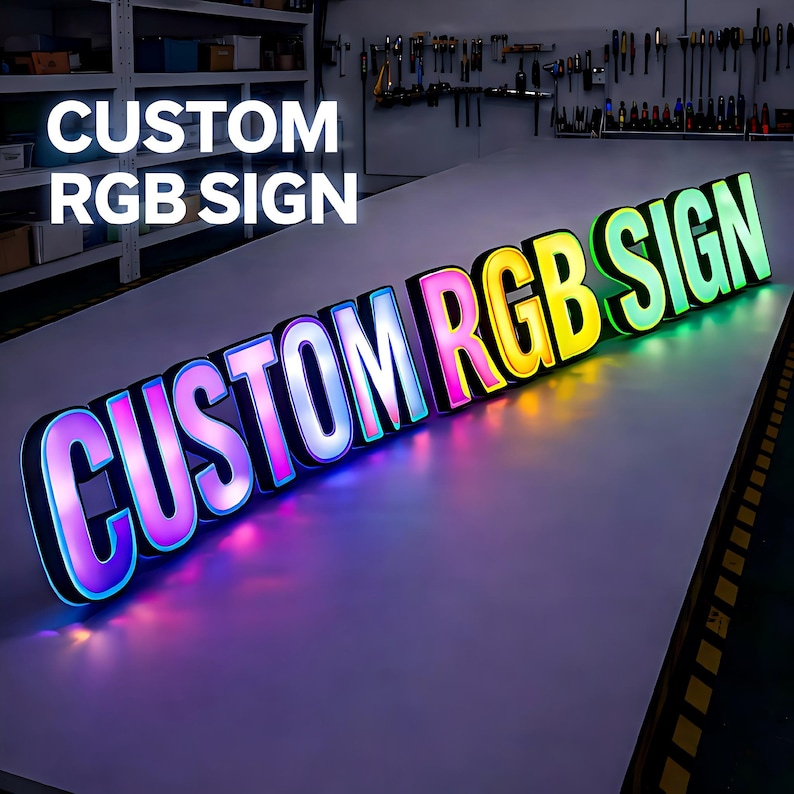 Pode incluir: Uma placa RGB personalizada com as palavras "CUSTOM RGB SIGN" em letras grandes e iluminadas. As letras s&atilde;o contornadas em preto e t&ecirc;m um gradiente de cores, incluindo rosa, azul, amarelo e verde. A placa est&aacute; em uma superf&iacute;cie branca.
