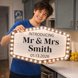 May include: A rectangular marquee-style sign with rounded corners and a border of small white LED lights. The white sign features black text that reads INTRODUCING Mr & Mrs Smith and the date 01.13.2026 in a clean, bold, sans-serif font.