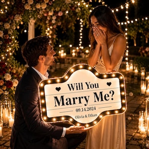 以下が含まれることがあります： Will You Marry Me?、日付14.09.2024、名前Olivia & Ethanの文字が入った、カスタムメイドのマーキー風ライトアップサイン。中央は白地で黒い文字が書かれ、ハートのアイコンと小さな電球で縁取られたデザイン。