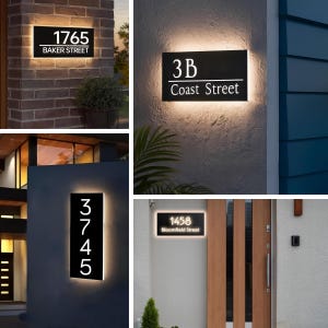 May include: A collection of illuminated address signs. Each sign features a black rectangular panel with white numbers and street names. The signs are mounted on various exterior walls, including brick and stucco, with a warm, inviting glow.