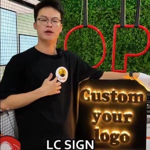 May include: A rectangular black sign featuring the illuminated text "Custom your logo" in a bold, serif font. The sign is positioned below a red circular frame and is accompanied by the text "LC SIGN" displayed at the bottom of the image.