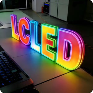May include: A set of illuminated 3D letters spelling LCLED, featuring a vibrant gradient color scheme that transitions from orange and yellow to blue and purple. Each letter has a thick, structured border and emits a bright, glowing light.