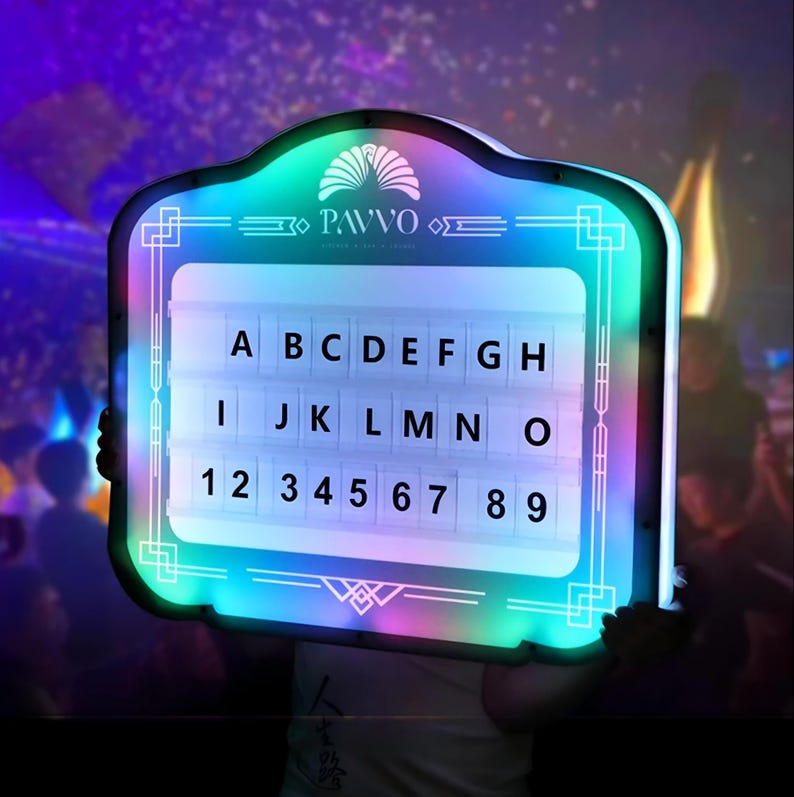 May include: A rectangular LED sign with a white interior, displaying letters and numbers. The sign has a colorful, glowing border and the word "PAVVO" at the top. The letters A through O and numbers 1 through 9 are visible.
