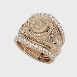 May include: A set of three gold rings. The largest ring features an oval center with an embossed design and the word "GUARDIAN". The other two rings are adorned with small, clear gemstones. The rings have intricate filigree detailing.