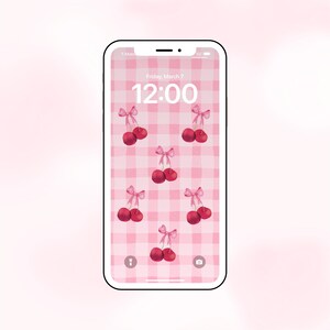 May include: A pink and white checkered phone background with a digital clock displaying 12:00 and several red cherries with pink bows.