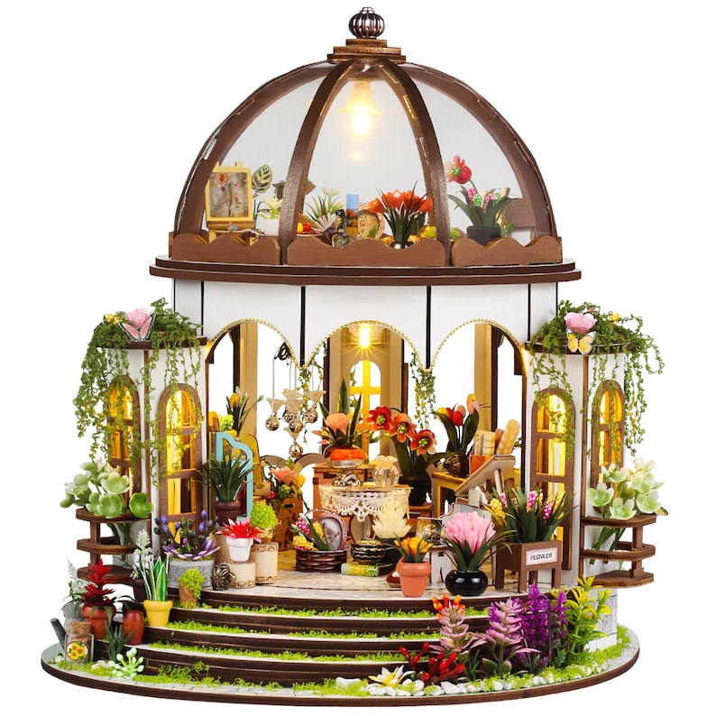 May include: A miniature wooden greenhouse with a domed glass roof, filled with tiny potted plants and flowers. The structure features arched windows, decorative trim, and a warm interior light, creating a charming, detailed scene.